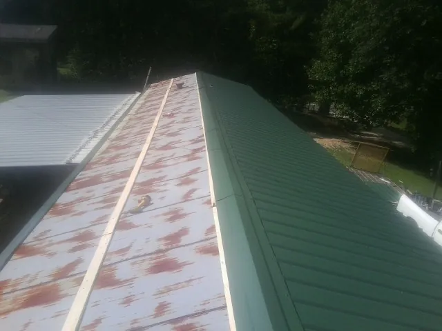 Old rusted panels beside newly installed green metal roofing — Wind Damage Roof Repair by Roofing Brothers in Alexander