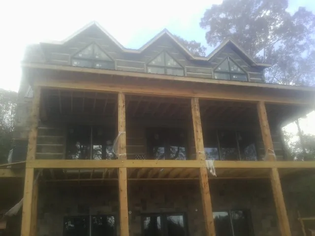Dormers and porch framing on a large log home under construction — Roof Coating work by our crew in Alexander